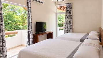 Une chambre d’hôtel avec deux lits, un téléviseur posé sur un meuble en bois et un appareil de climatisation.