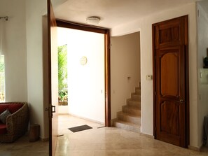 An open doorway leading to a staircase, a wooden door, and a red cushioned chair. - Just 5 minutes from the beach! An ideal home for families or groups. (Ixtapa Zihuatanejo)