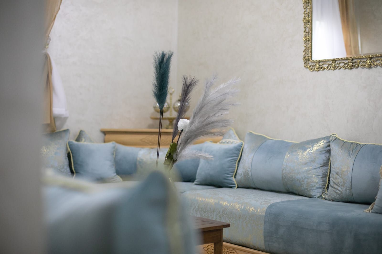 Ein Wohnzimmer mit einem hellblauen Sofa, einem Holztisch und dekorativen Federn.