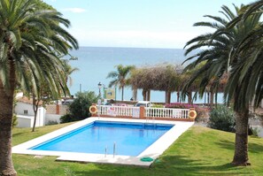 A rectangular swimming pool with a white deck, surrounded by palm trees and a view of the sea. - Studio in Nerja Near Carabeillo Beach (Nerja)