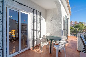 A balcony with a table and chairs, a sliding glass door, and a view of the street. - Holiday Home in Nerja With Sea Views (Nerja)