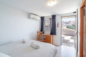 A bedroom with a bed, a desk, and a chair. There is a window with curtains and a view of buildings outside. - Holiday Home in Nerja With Sea Views (Nerja)