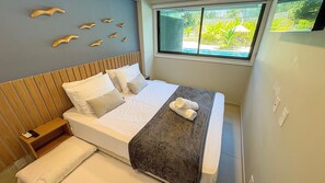 Ein Bett mit weißen Laken, einer grauen Decke und zwei aufgerollten Handtüchern.