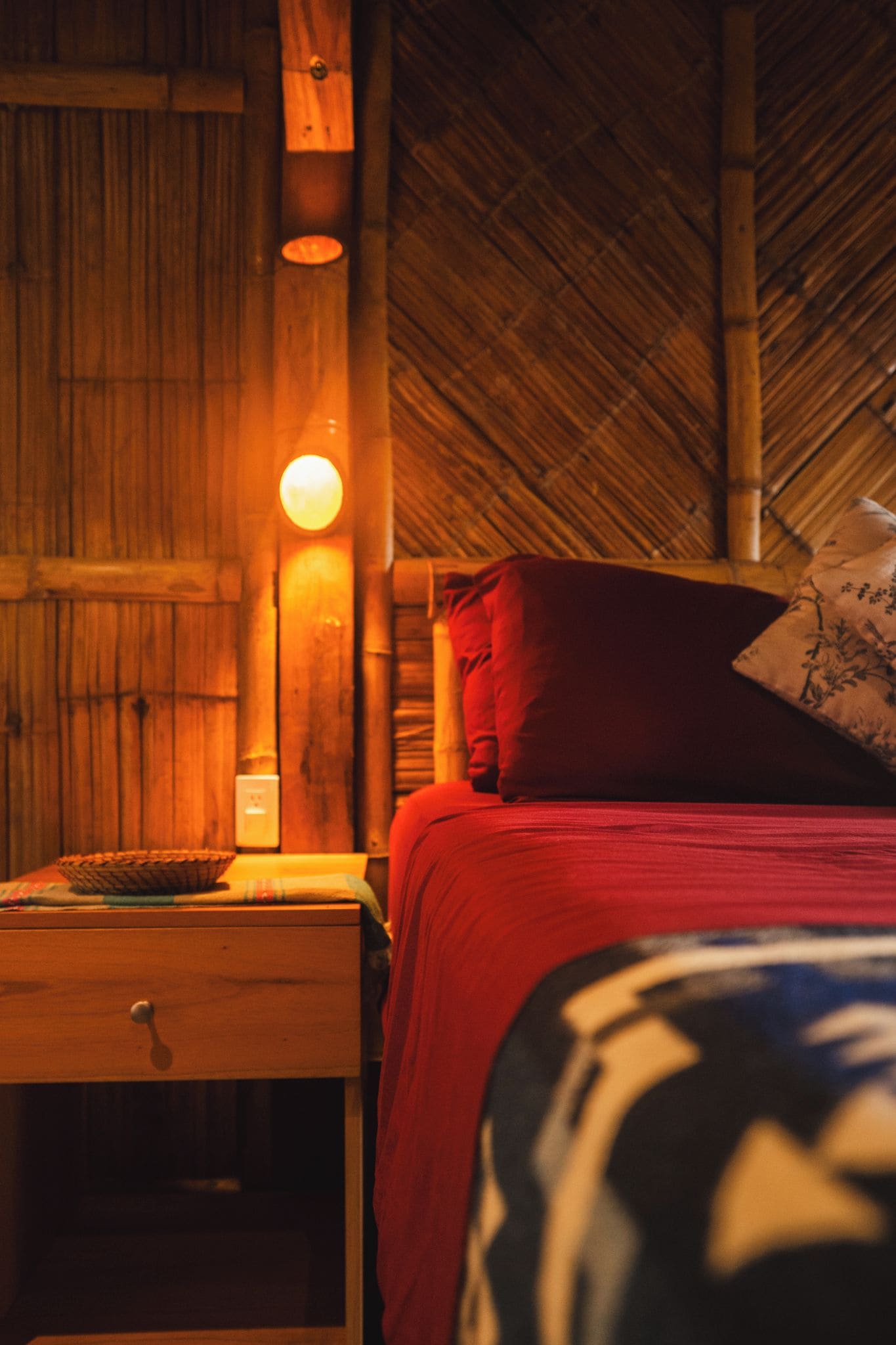 A room with a bed, a nightstand, and a wall-mounted lamp.