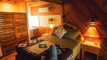 Une chambre mansardée chaleureuse, avec un lit, une table de chevet et une armoire en bois.