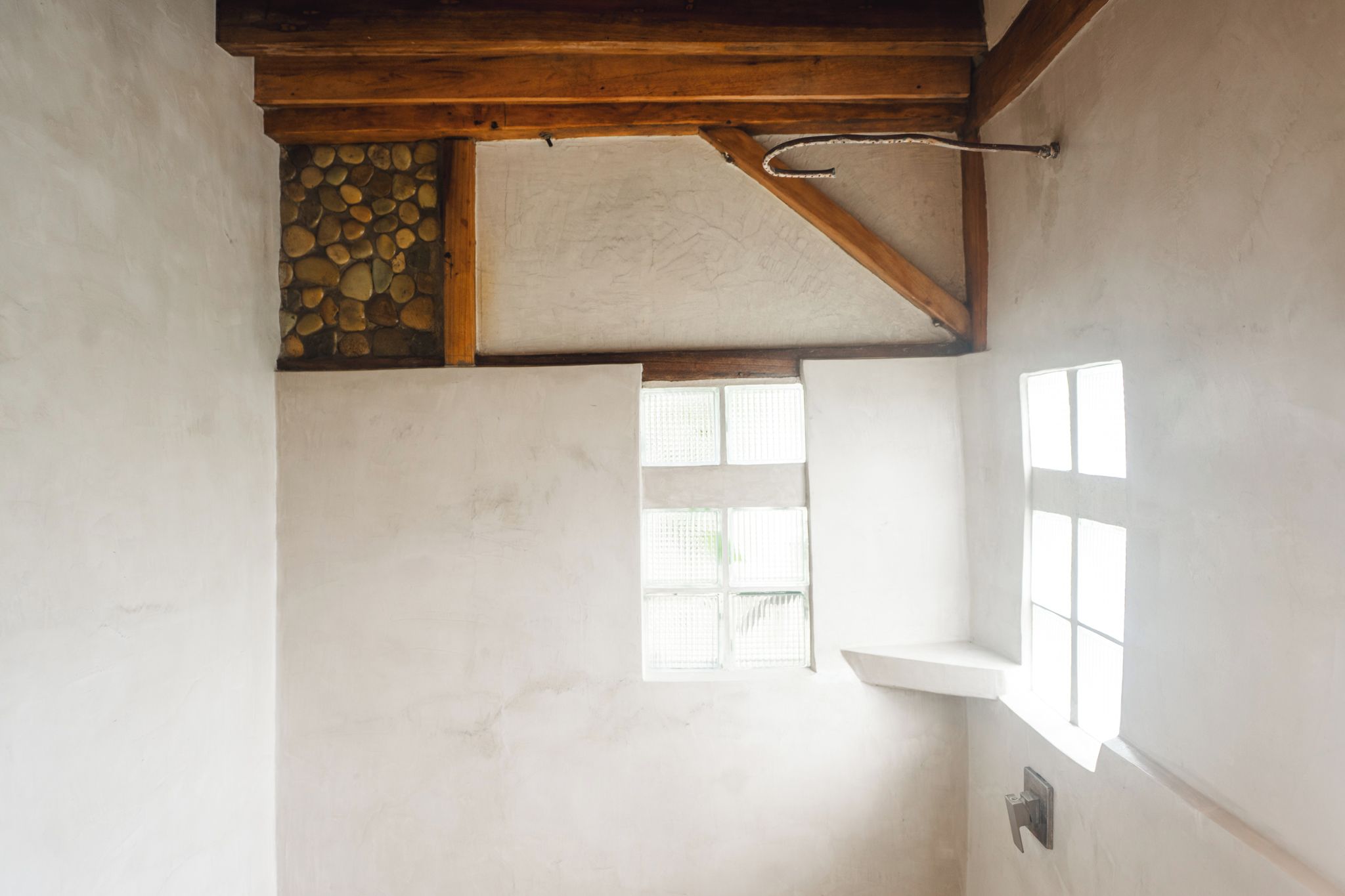 Une pièce avec un mur en pierre, un plafond avec une poutre en bois et une fenêtre donnant sur un beau paysage.