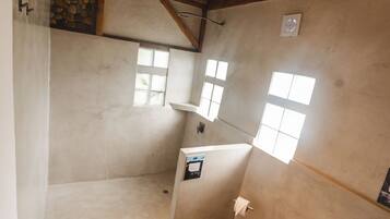 Une salle de bain avec des toilettes, un espace douche et un tapis rouge.