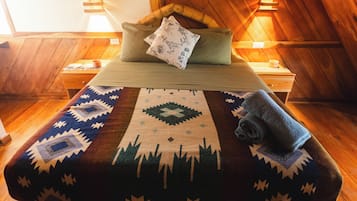 Ein gemütliches Zimmer mit einem hölzernen Bett, einem Nachttisch und einem Wandheizgerät.