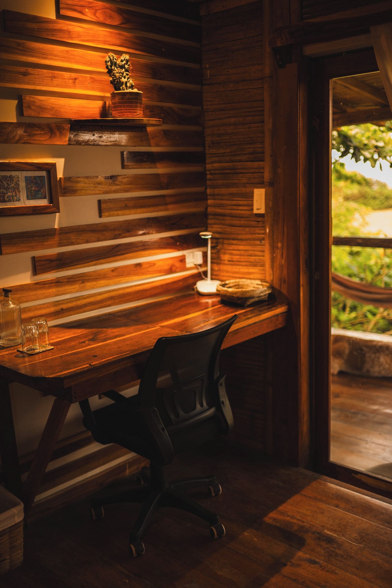 A wooden desk with a chair, a lamp, and a small plant.