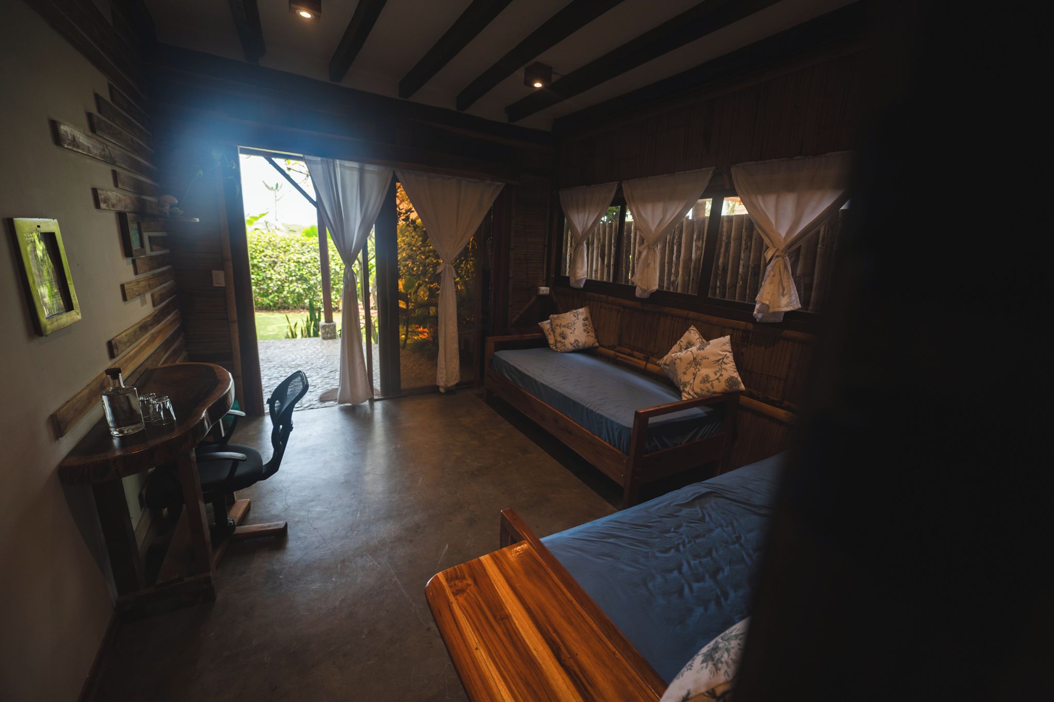 Une chambre confortable avec un lit, une chaise et une petite table. Il y a une fenêtre avec des rideaux et une vue sur la verdure à l’extérieur.