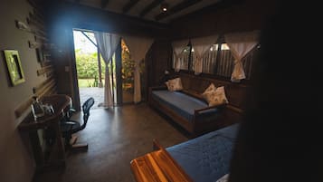 Une chambre confortable avec un lit, une chaise et une petite table. Il y a une fenêtre avec des rideaux et une vue sur la verdure à l’extérieur.