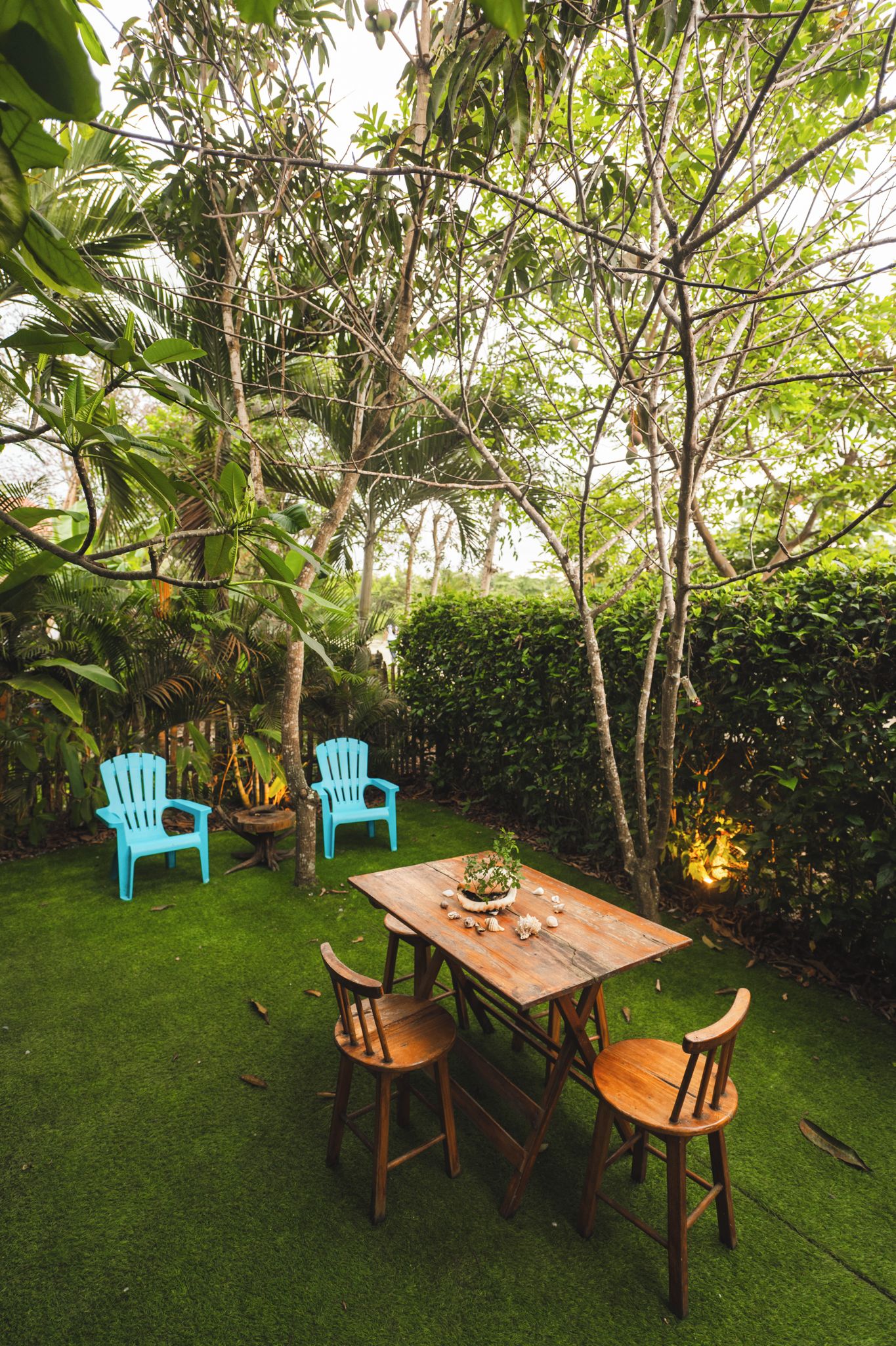 Una mesa de madera con sillas en un jardín exuberante.