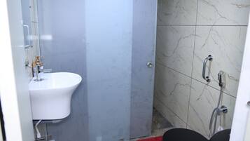 A bathroom with a white sink, a shower with a handheld showerhead, and a glass door.