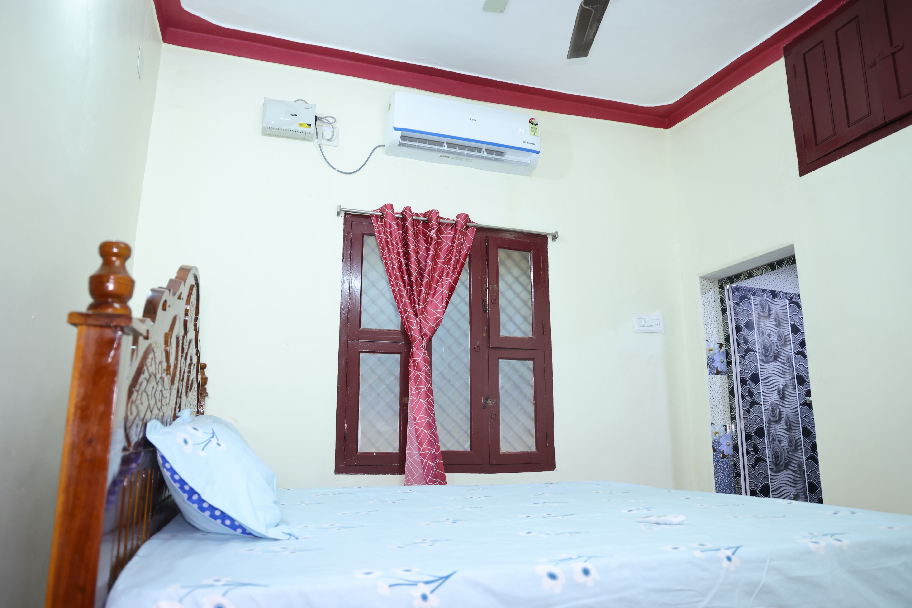 Un dormitorio con cama, ventana con cortinas, equipo de aire acondicionado y puerta.