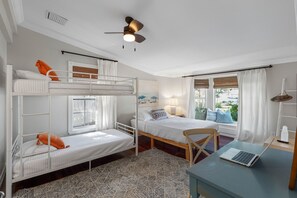 A room with bunk beds, a desk with a laptop, a ceiling fan, and a window with curtains. - Screened HTD Pool/SPA + Game RM + 15 Min to Beach + Luxury Design + Many Beds (Clearwater)