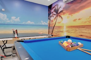 A pool table with a sunset mural, a ping pong table, and a pool cue rack. - Screened HTD Pool/SPA + Game RM + 15 Min to Beach + Luxury Design + Many Beds (Clearwater)