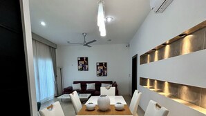 Uma sala de jantar moderna com uma mesa e cadeiras brancas, e um ventilador de teto.