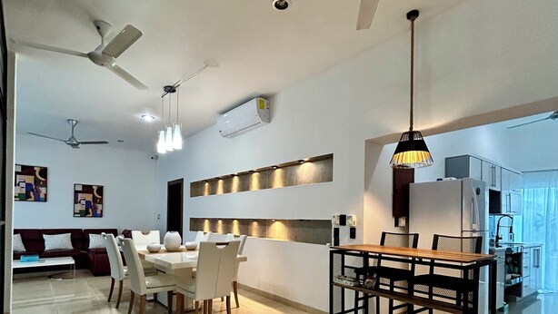 Sala de estar moderna com área de jantar, ventiladores de teto e iluminação embutida.