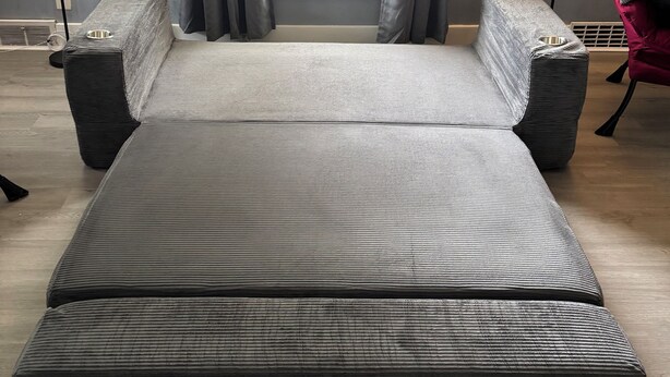 Een moderne slaapkamer met een groot bed, twee nachtkastjes, een rode fauteuil en een raam met gordijnen.