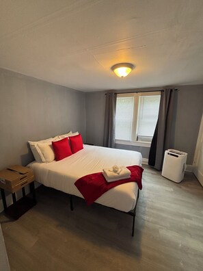 Una habitación de hotel con una cama, una mesita de noche, una ventana con cortinas y un calentador.