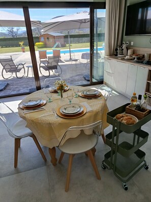 Ein Essbereich mit einem Tisch für vier Personen, einem Fernseher und Blick auf den Garten.