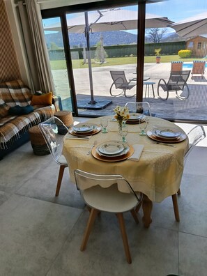 A dining area with a table set for four, chairs, and a view of the outdoors. - THE LITTLE HOUSE AND ITS SWIMMING POOL (Gourdan-Polignan)