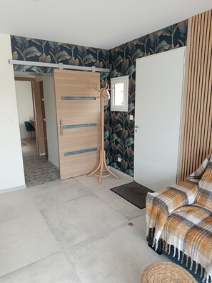 A bedroom with a bed, a wooden wardrobe, a coat rack, and a door leading to a bathroom. - THE LITTLE HOUSE AND ITS SWIMMING POOL (Gourdan-Polignan)
