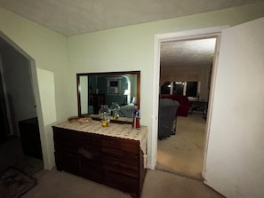 Ein Zimmer mit einem Holzkasten, einem Spiegel und einem Durchgang zu einem anderen Raum.