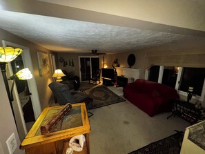 Ein Wohnzimmer mit Kamin, einem roten Sofa, einem Holztisch und einem Fernseher.