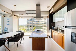 A modern kitchen with a central island, built-in appliances, and a view of a high-rise building. - Beachfront Peninsula Puerto Vallarta, ocean and mountain views, 2 bedrooms. (Puerto Vallarta)