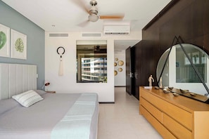 A modern bedroom with a bed, a dresser, a ceiling fan, and a large mirror. - Beachfront Peninsula Puerto Vallarta, ocean and mountain views, 2 bedrooms. (Puerto Vallarta)