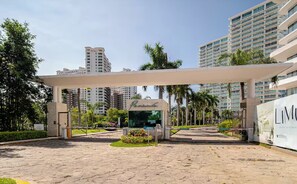 A hotel entrance with a covered walkway, palm trees, and modern buildings in the background. - Peninsula Puerto Vallarta, near the beach, with ocean and mountain views, 2 bedrooms. (Puerto Vallarta)