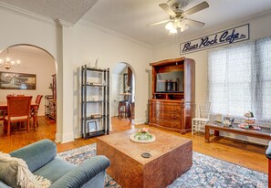Un salon avec une table basse, des canapés et une bibliothèque. On aperçoit à l’arrière-plan un coin repas avec des chaises et une table.