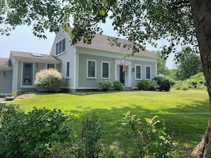 A two-story house with a well-maintained lawn and a flag.