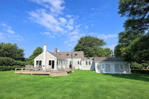 A two-story house with a deck and a separate garage. - Historic home on Bailey Island with ocean views. Steps from the Giant's Stairs. (Bailey Island)