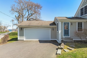 A single-story house with a garage, a front porch, and a small detached structure with a blue door. - Historic home on Bailey Island with ocean views. Steps from the Giant's Stairs. (Bailey Island)