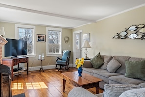 A living room with a television, a sofa, a coffee table, and a chair.