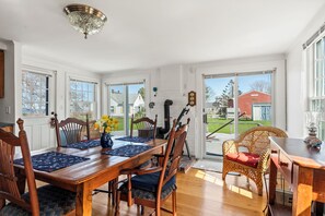 A dining room with a wooden table, chairs, and a view of the outside.