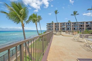 A beachfront hotel with a pool area, outdoor seating, and a view of the ocean. - Oceanfront budget friendly 1 bedroom condo, walkable area (Napili-Honokowai)