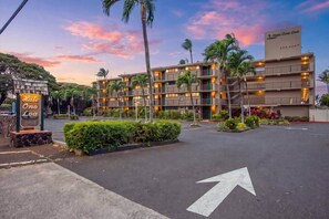 A hotel with a sign reading 'Hale Ola Loa,' featuring a multi-story building with balconies, a parking lot, and a clear sky. - Oceanfront budget friendly 1 bedroom condo, walkable area (Napili-Honokowai)