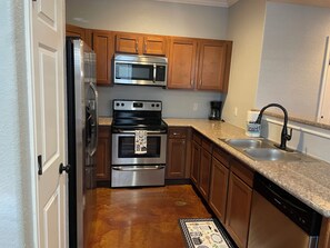 A kitchen with wooden cabinets, stainless steel appliances, a granite countertop, and a built-in dishwasher. - Home SWEET Home away from home! Selma, TX! (Selma)