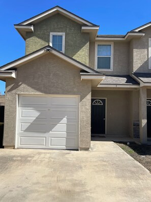 A two-story house with a garage, a front door, and a small porch area. - Home SWEET Home away from home! Selma, TX! (Selma)