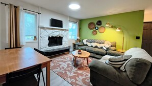 Ein Wohnzimmer mit Kamin, einer Couch, einem Couchtisch und einem Essbereich mit Tisch und Stühlen.