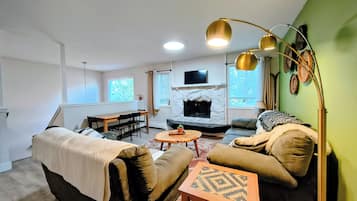 Een woonkamer met een open haard, bank en een eethoek.