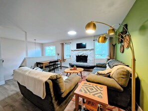 A living room with a fireplace, sofa, and a dining area.
