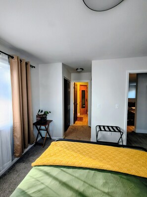 Une chambre d’hôtel avec un lit, un bureau et une vue sur le couloir.