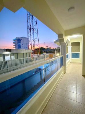 Ein Balkon mit einem Pool, Blick auf ein Gebäude und ein Strommasten.