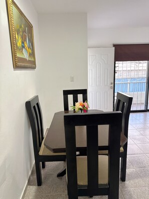 Ein Essbereich mit Tisch und Stühlen, einem Bild an der Wand und einer Tür, die auf einen Balkon führt.