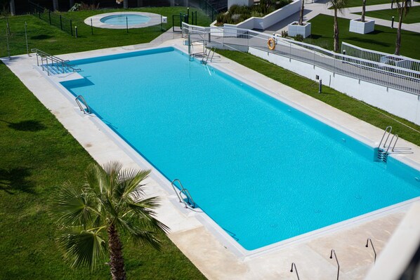 A rectangular swimming pool with a surrounding deck, a lifeguard stand, and a palm tree. - Apartment in Nerja With Sea Views & Pool (Torrox)