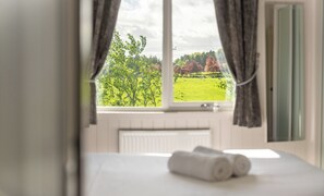 Une chambre avec une fenêtre, un lit et une vue sur un champ verdoyant.
